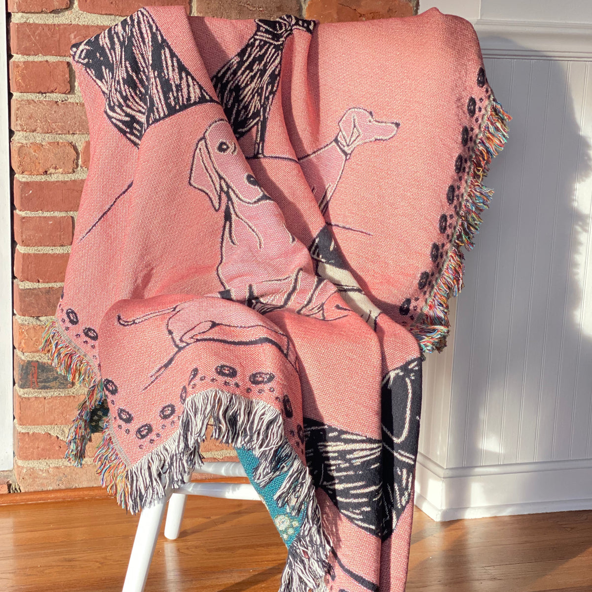 The pink dog blanket draped over a white chair, a cream retriever and navy pups on pink. Sweet and playful.